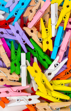 Multicoloured wooden clothes pegs on a white background.