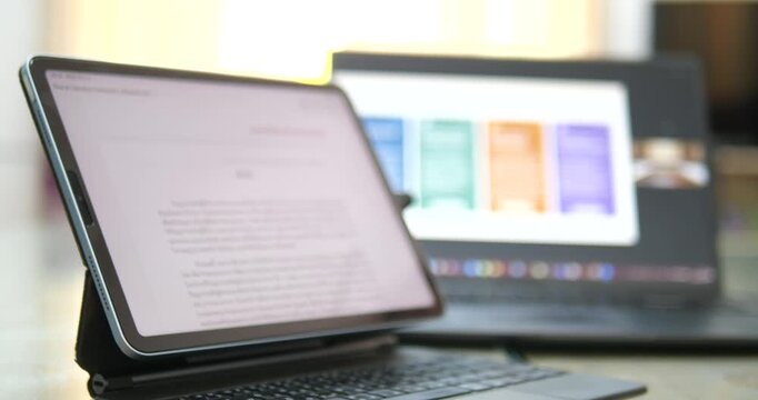 Close up of tablet on desk with laptop in background