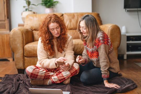 Two people sitting on a blanket in a living room engaging with a