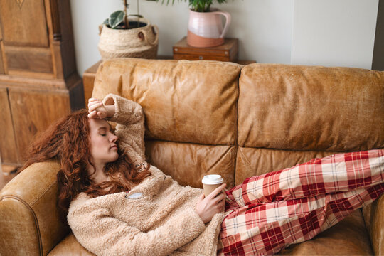 Person resting on a couch with coffee in a cozy room during a