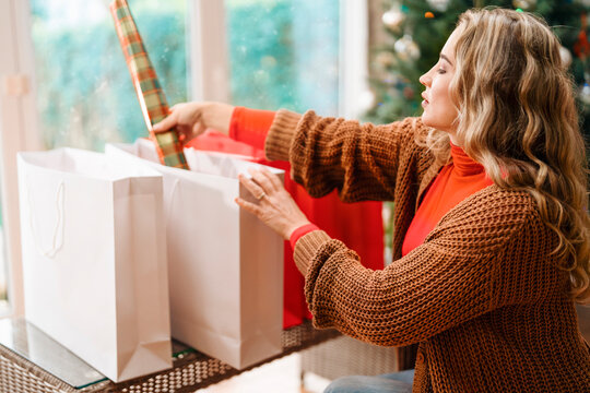Woman wrapping gifts at home during the holiday season with