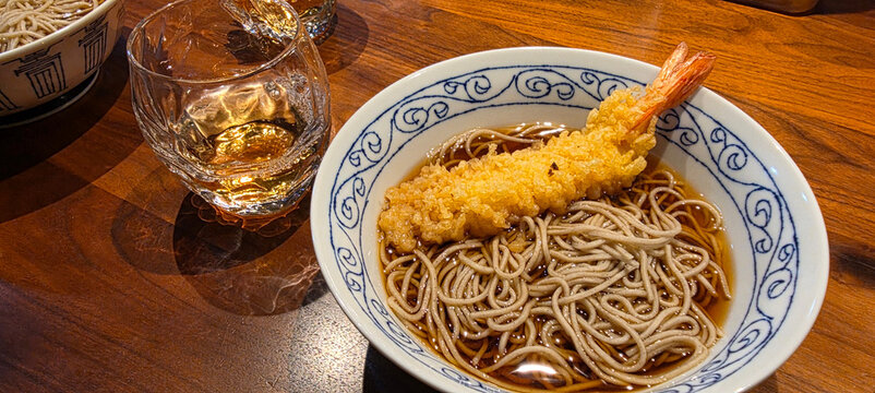 Tempura shrimp soba noodles in a patterned bowl on a wooden table