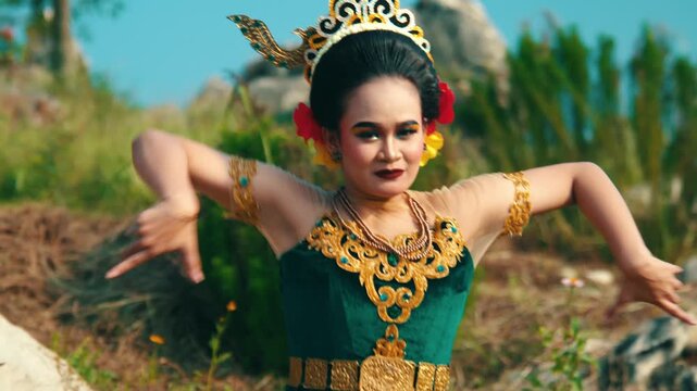 Footage of a female performer in traditional attire executing a dance sequence that involves spreading her arms and then crossing them over her chest.