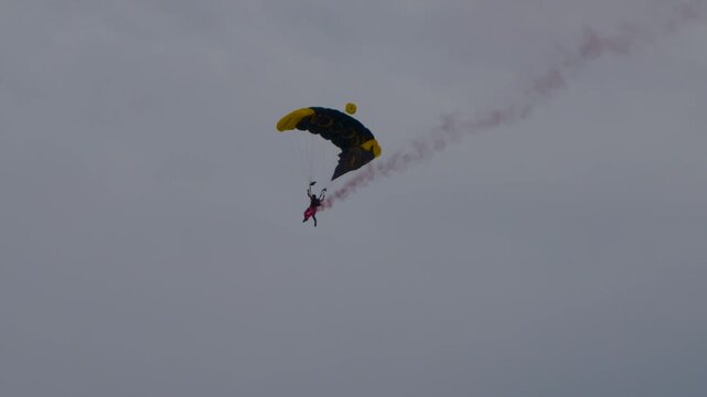 Parachute glider falling to the ground with a smoke trail