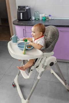 Happy baby sitting in high chair looking away during mealtime