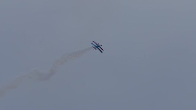 Propeller Biplane doing stunts with smoke trail at an air show