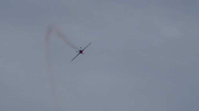 Propeller plane doing stunts with smoke trail at airshow