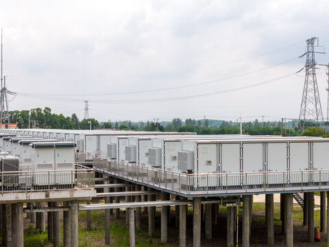 Outdoor elevated energy storage container facility with power transmission towers in background