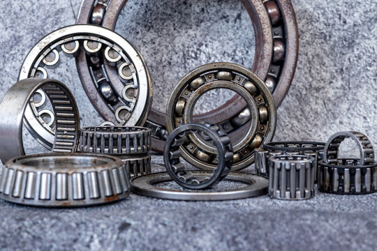 Various industrial roller and ball bearings arranged on concrete workshop floor.