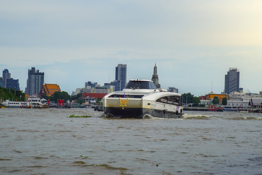 Bangkok, Thailand - June  16, 2026 : An electric passenger boat traveling on the Chao Phraya River passes the prang of Wat Arun, a beautiful viewpoint and a symbol of Bangkok.