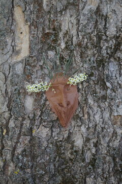 Terracotta tree spirit face sculpture decorated with white spring flowers