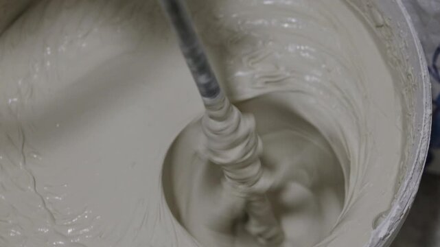 Thick plaster mixture being stirred in bucket for wall finishing