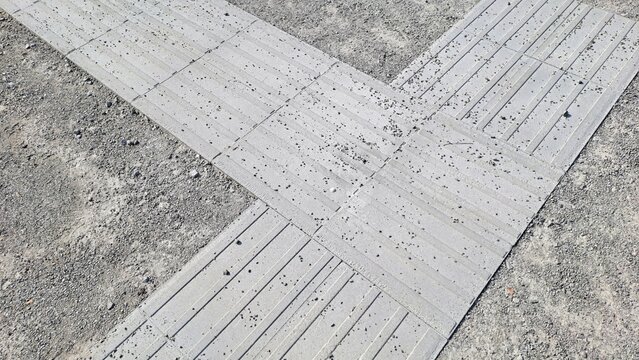 Percorso tattile a pavimento progettato per assistere le persone non vedenti, collocato su una superficie urbana in acciottolato.