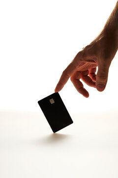 Male Hand Reaching for a Blank Black Credit Card on White Background