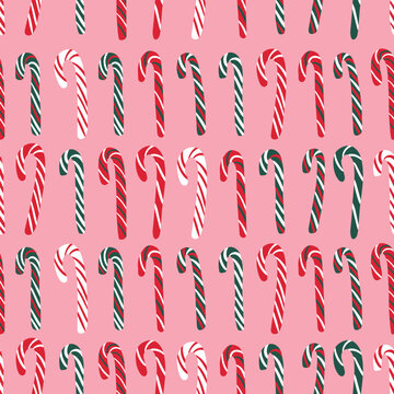 Seamless Christmas pattern with red, green and white striped candy canes on a pink background. Cute festive peppermint candy design