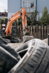Orange excavator with bucket at an urban residential construction site, surrounded by gravel © Natalia Schuchardt