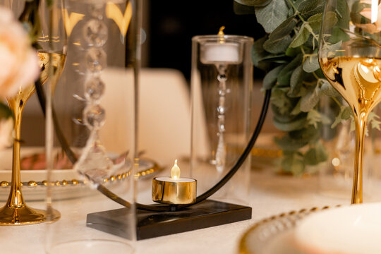 Elegant dinner table centerpiece with tea light candle and gold glasses