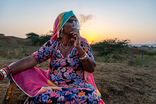Rajasthani woman from Pushkar, Rajasthan enjoys a cigarette puff during sunset