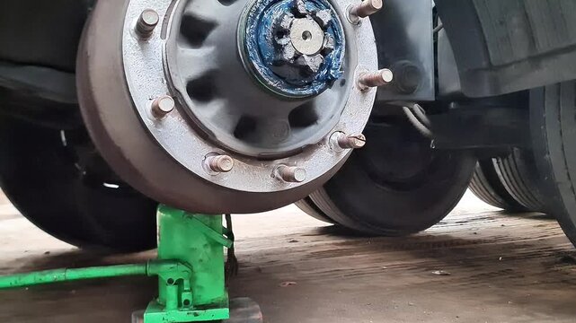 Broken Down Semi Truck Axle Lifted by Bottle Jack During Roadside Wheel Repair