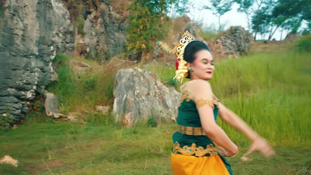 A dynamic shot of a Javanese dancer turning her body around while performing graceful hand gestures, showing back detail of costume.