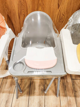 Baby high chair wrapped in protective plastic film for hygiene in family restaurant with individual silicone bib placed on tray. Child-friendly dining service and hospitality concept.