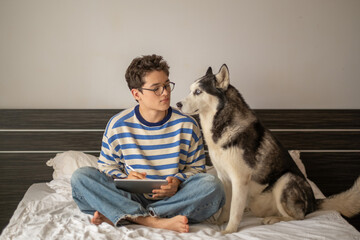 Young student working together with husky lying close, company better than any classmate, frame worth keeping in whole collection. Wide shot. Concept of studying together with own dog © iwavephoto