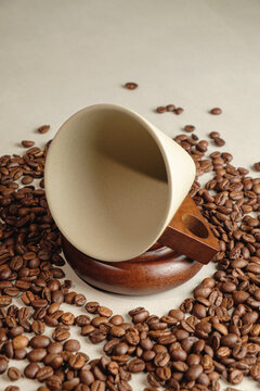 Coffee cup resting on wooden coaster surrounded by roasted coffee