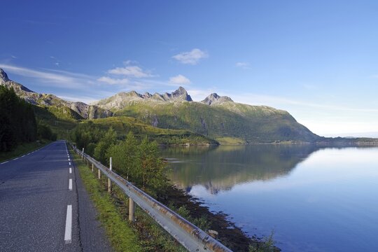 Steep mountains reflected in the sea, fjord, shore, road without traffic, Jektvik, Kystriksveien, FV 17, Helgeland, Nordland, Norway
