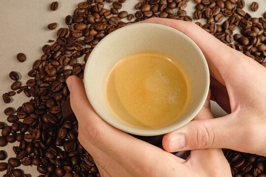 Holding a warm cup of espresso surrounded by rich coffee beans