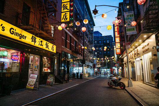 New York City, New York, USA - 08.05.2024: A vibrant Chinatown street glows with colorful lanterns and neon signs during the evening in the city. Restaurants, shops, and illuminated signs create a