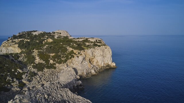 Drone shot, A rocky coastline with steep cliffs, calm sea and a clear blue sky, Anthony Quinn Bay, Vagies Bay, Rhodes, Dodecanese, Greek Islands, Greece
