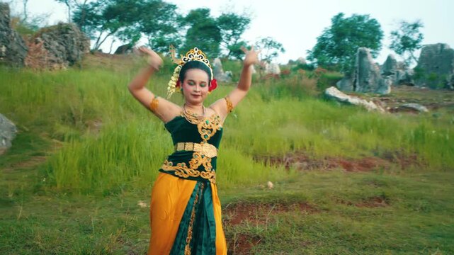 Medium-wide shot capturing the expansive and expressive arm movements of a dancer, highlighting the flow of her traditional attire.