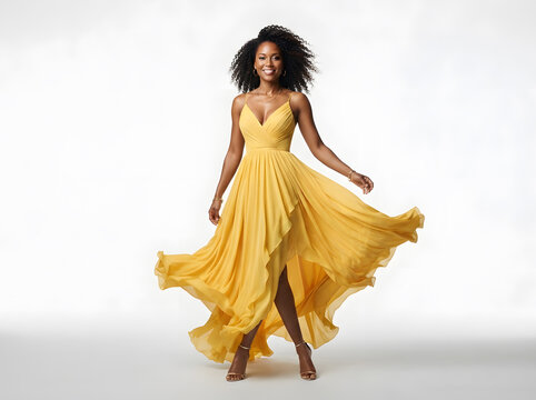 Professional woman in elegant yellow gown posing dynamically with flowing skirt against neutral background