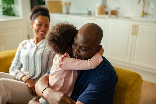 Father hugs child on couch while mom smiles