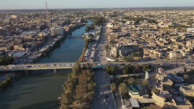 Slow aerial pan over the city of Hilla along the Shatt al-Hilla river, Iraq