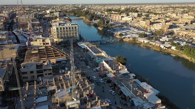 Aerial tracking shot over the city of Hilla along the Shatt al-Hilla river, Iraq