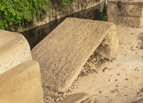 A weathered stone slab positioned for manual laundry cleaning beside a water channel, reflecting the traditional labor of historical washerwomen