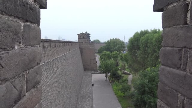 Ancient Ming dynasty city wall with watchtower and battlements in Pingyao, Shanxi, China, framed by crenellations
