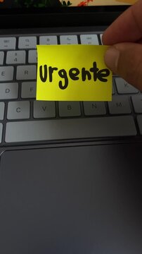 Mano sosteniendo nota urgente sobre teclado de laptop