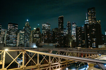 Illuminated skyscrapers of Lower Manhattan rise behind the steel structure of the Brooklyn Bridge...
