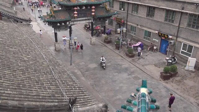 High angle view of a traditional Chinese archway with red lanterns and street life in the ancient city of Pingyao, Shanxi, China
