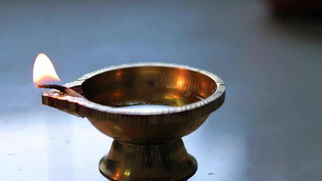 Traditional Oil Lamp with Burning Wick on a Reflective Surface