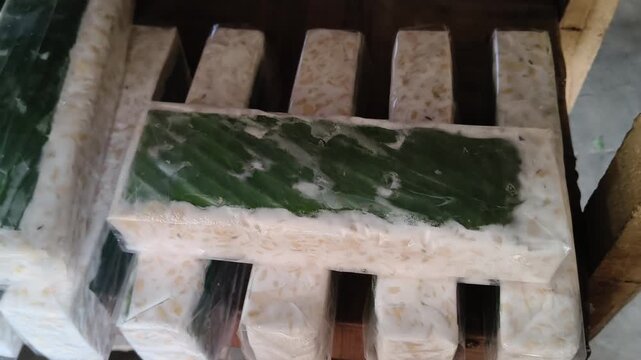Slicing fresh tempeh on wooden board for cooking