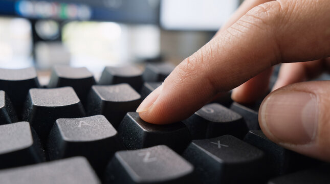 extreme close-up of finger pressing a computer keyboard key for digital technology and data entry concept