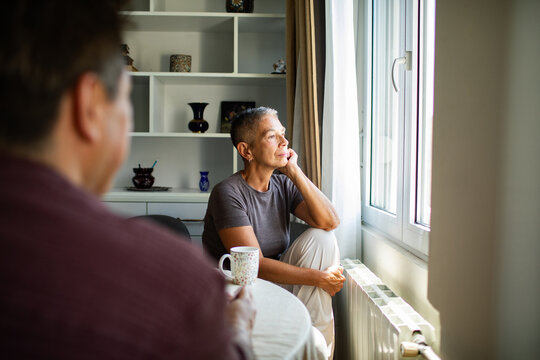 Older woman looking out the window at home