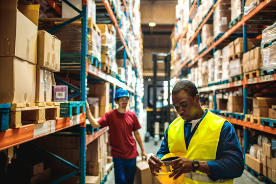 Warehouse worker taping hard hat in storage aisle