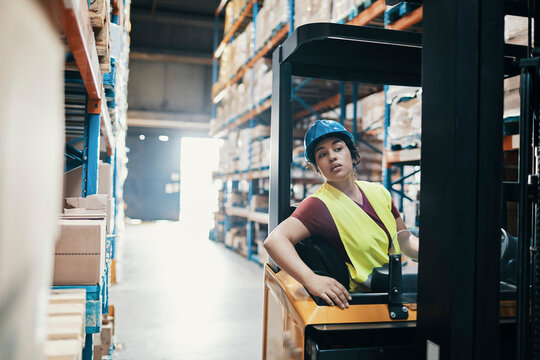 Warehouse worker reversing a forklift in storage aisle