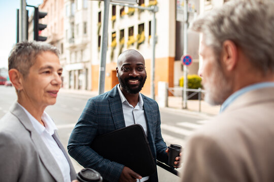 Smiling businessman with colleagues talking on city street