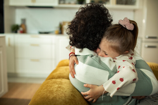 Parent hugging child on couch in home kitchen