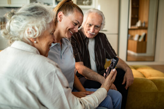 Young woman helps seniors video call at home